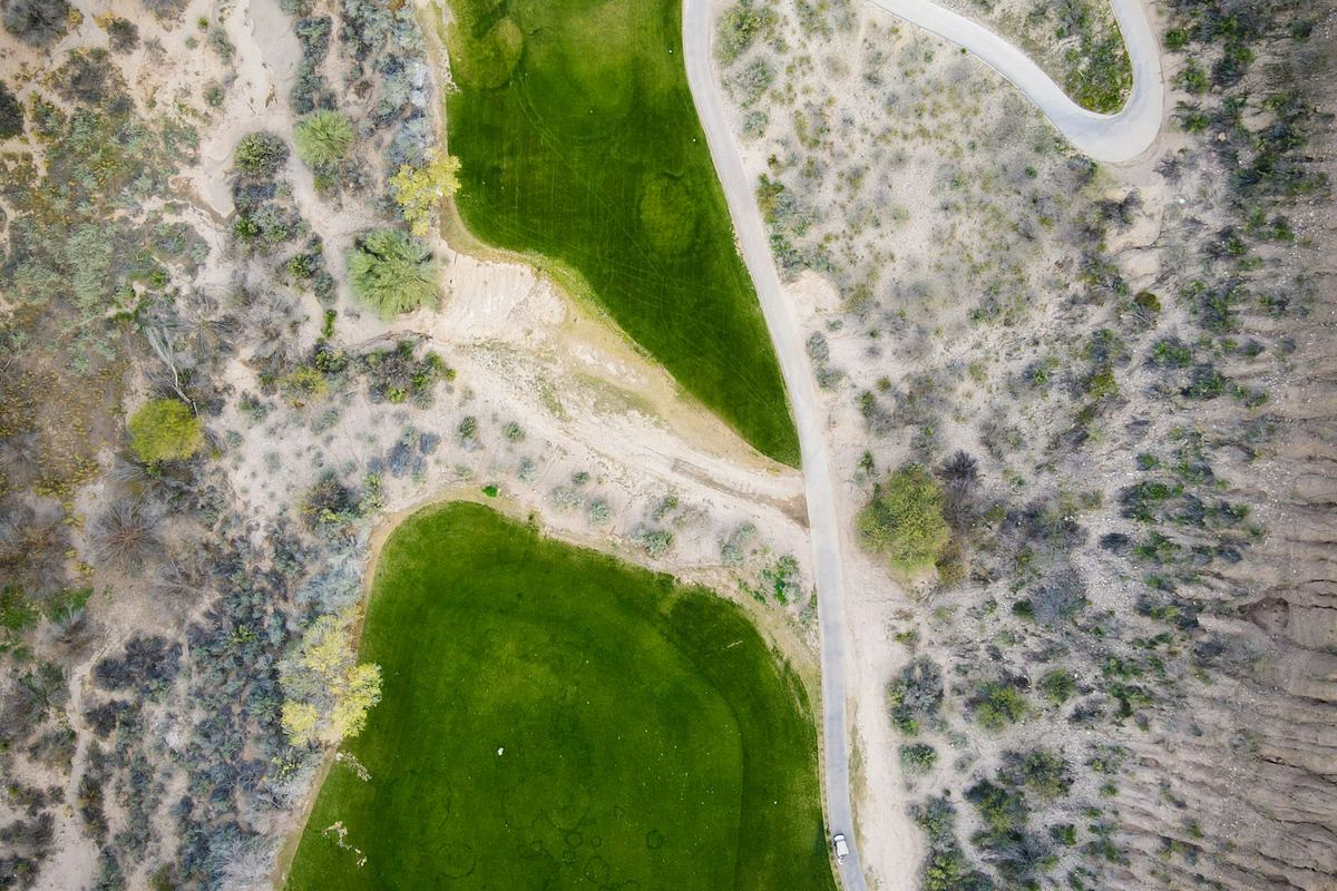 Aerial view of a green golf course fairway winding through Arizona desert landscape