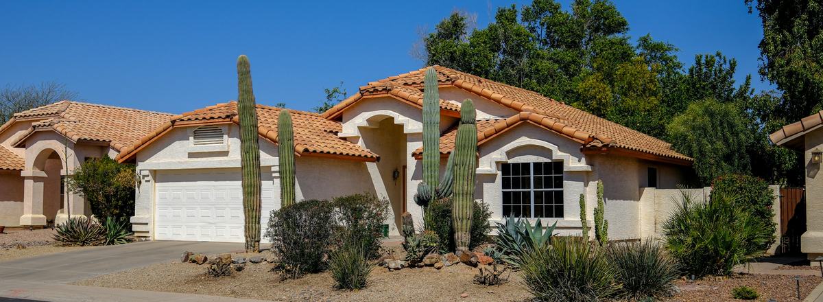 A single-story stucco home with a tile roof and desert landscaping